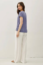 Load image into Gallery viewer, Woman wearing a purple t-shirt and white pants on a white background