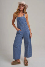 Load image into Gallery viewer, Woman wearing blue striped overalls and a white hat on a plain background