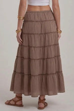 Load image into Gallery viewer, A woman wearing a brown and beige gingham tiered maxi skirt with a white crop top and brown strappy sandals, shown from the waist down against a light gray studio background.