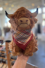 Load image into Gallery viewer, Stuffed toy Highland cow with a plaid scarf held in a hand against a blurred indoor background