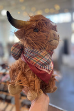 Load image into Gallery viewer, Plush toy cow with a plaid scarf held in front of a blurred indoor background