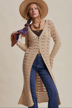 Load image into Gallery viewer, Woman wearing a long beige cardigan, blue jeans, and a wide-brimmed hat on a beige background