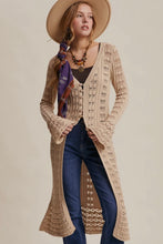 Load image into Gallery viewer, Woman wearing a long beige crochet cardigan with a neutral background