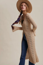 Load image into Gallery viewer, Woman wearing a long beige cardigan and a wide-brimmed hat on a plain background