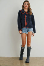 Load image into Gallery viewer, Woman wearing a dark blue jacket with red trim, denim shorts, and black rain boots on a plain background