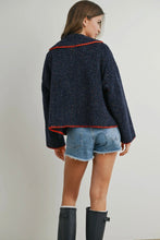 Load image into Gallery viewer, Woman wearing a dark blue jacket with orange trim, denim shorts, and black boots on a plain background