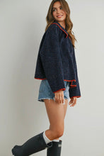 Load image into Gallery viewer, Woman wearing a navy blue sweater with red trim, denim shorts, and black boots on a plain background
