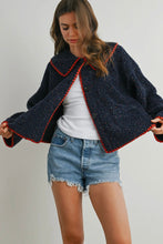 Load image into Gallery viewer, Woman wearing a dark blue jacket with red trim, white shirt, and denim shorts on a plain background