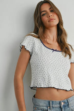 Load image into Gallery viewer, Woman wearing a white patterned top and blue jeans against a plain background