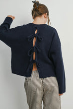 Load image into Gallery viewer, Person wearing a navy blue sweater with a bow detail at the back, standing against a plain background.