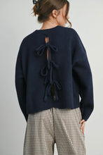Load image into Gallery viewer, Person wearing a navy blue sweater with bow details on a plain background