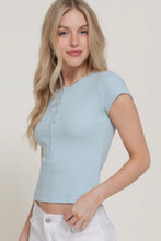 Load image into Gallery viewer, Woman wearing a light blue top and white pants against a plain background