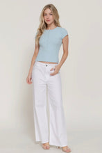 Load image into Gallery viewer, Woman wearing a light blue top and white pants on a plain background