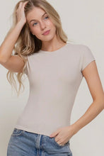 Load image into Gallery viewer, Woman wearing a beige t-shirt and blue jeans against a plain background