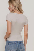 Load image into Gallery viewer, Woman wearing a beige t-shirt and blue jeans on a plain background