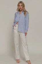 Load image into Gallery viewer, Woman wearing a light blue button-up shirt and white pants on a plain background