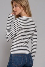 Load image into Gallery viewer, Woman wearing a black and white striped long-sleeve shirt and blue jeans on a gray background