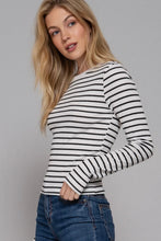 Load image into Gallery viewer, Woman wearing a black and white striped long-sleeve top against a gray background