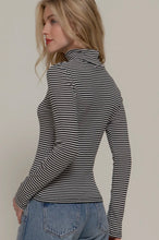 Load image into Gallery viewer, Woman wearing a black and white striped long-sleeve top and blue jeans against a plain background