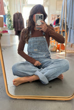 Load image into Gallery viewer, Person wearing denim overalls sitting on a mirror in a store.