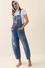 Load image into Gallery viewer, Woman wearing denim overalls with star patches on a beige background