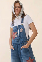 Load image into Gallery viewer, Woman wearing a denim dress with star patches on a beige background